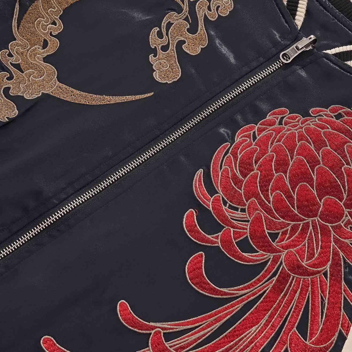 Detail — crescent-moon embroidery and zipper track beside flowing chrysanthemum petals.