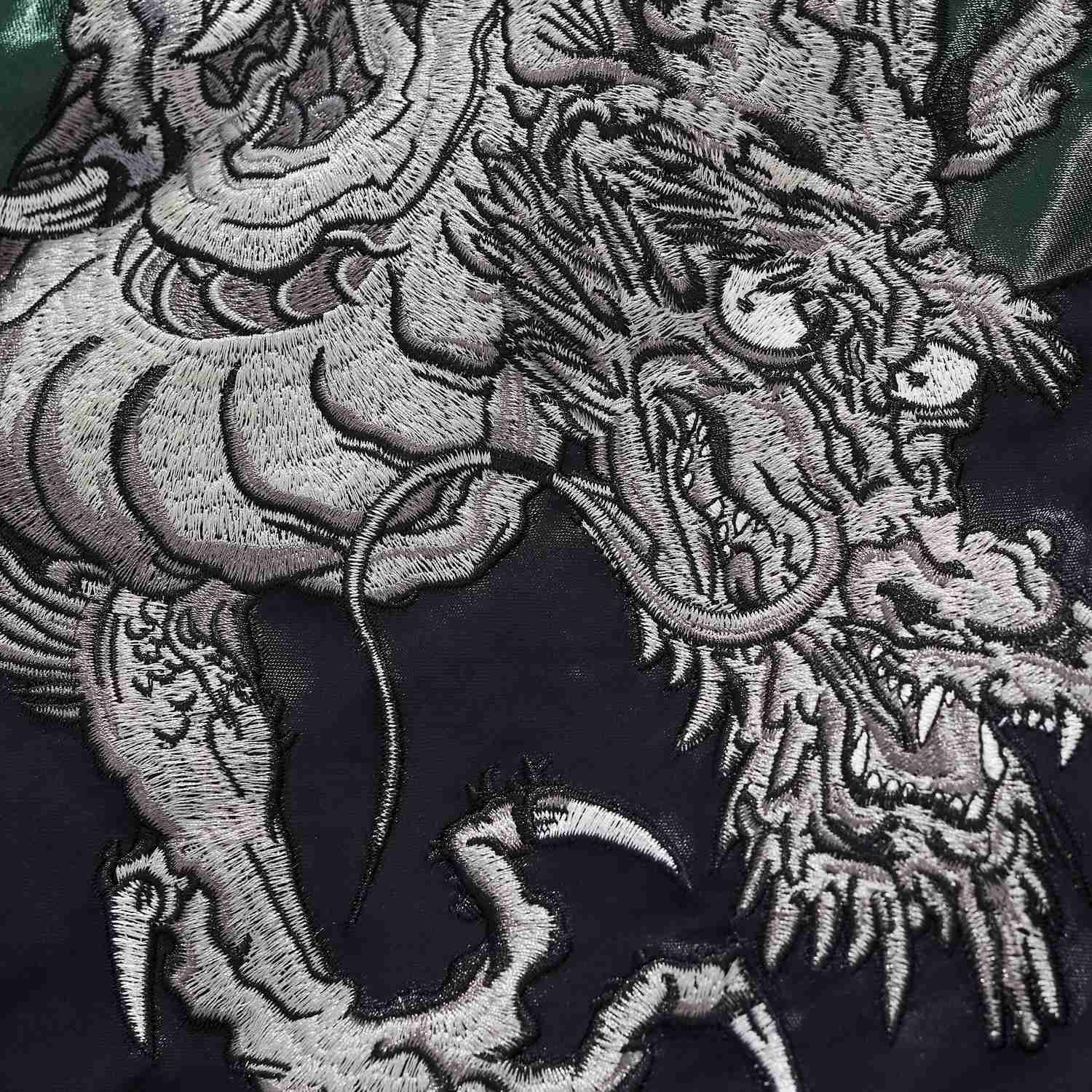 Dragon head and claw embroidery close-up with sharp fangs and whiskers.