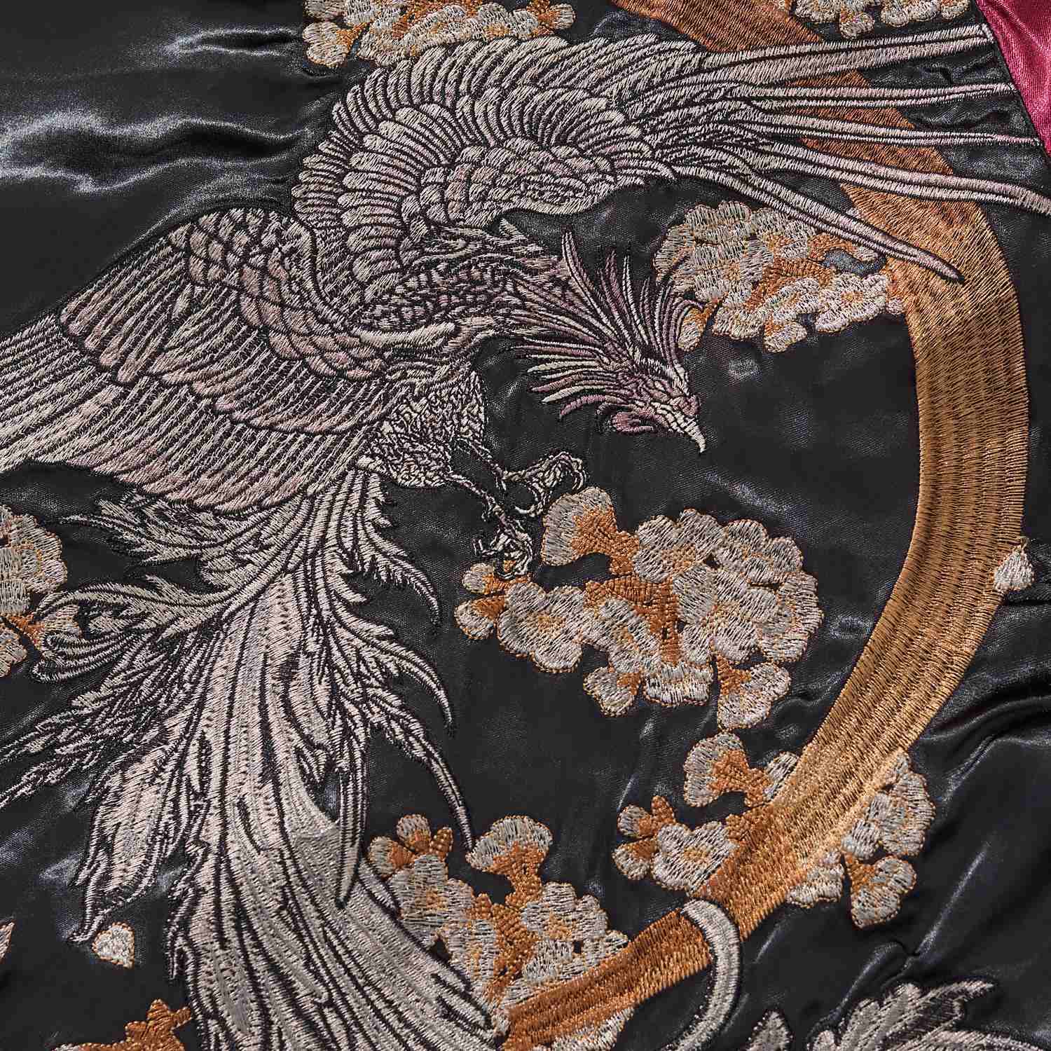 Phoenix embroidery close-up with flowing tail feathers and blossoms.