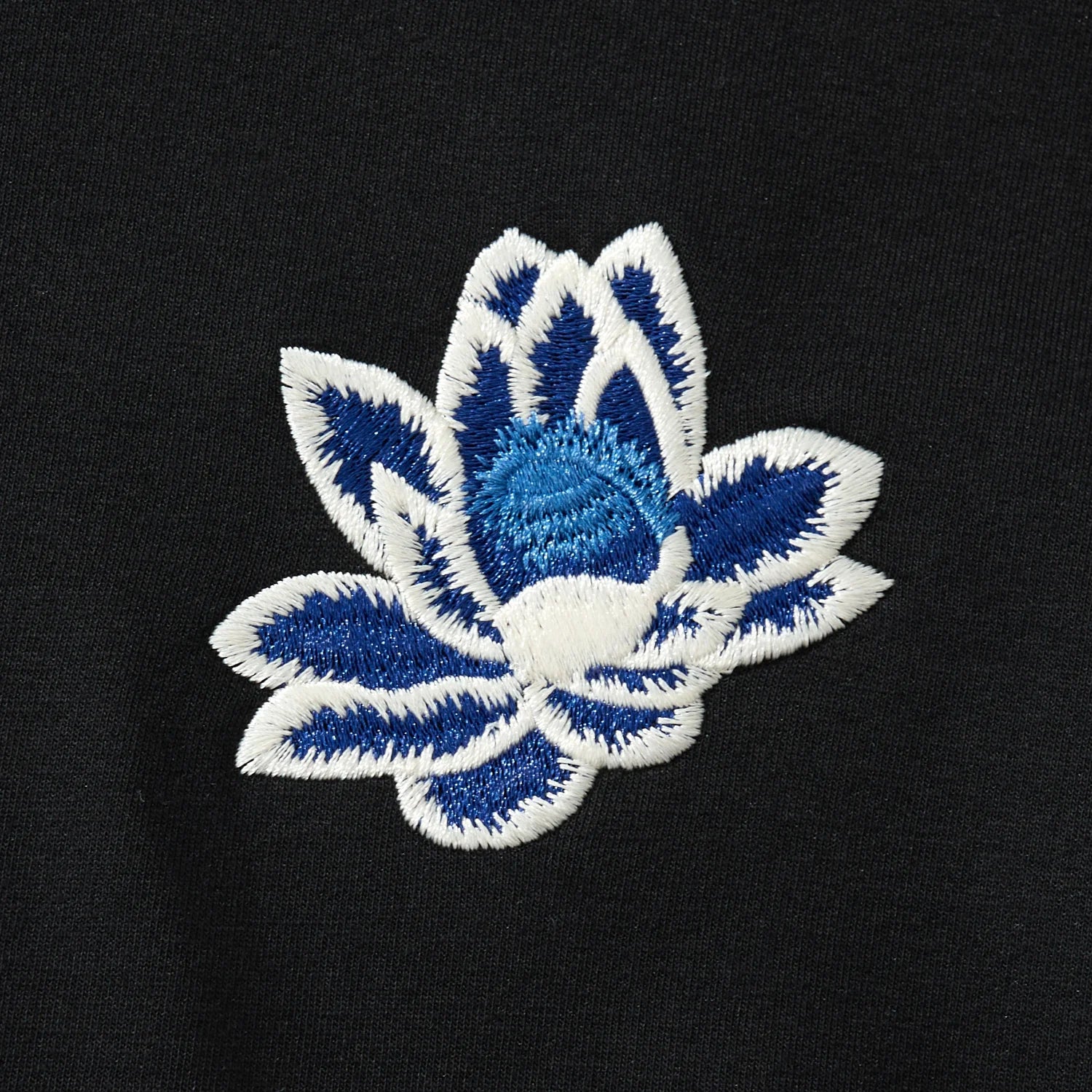 Chest lotus embroidery close-up on the black hoodie with clean edges