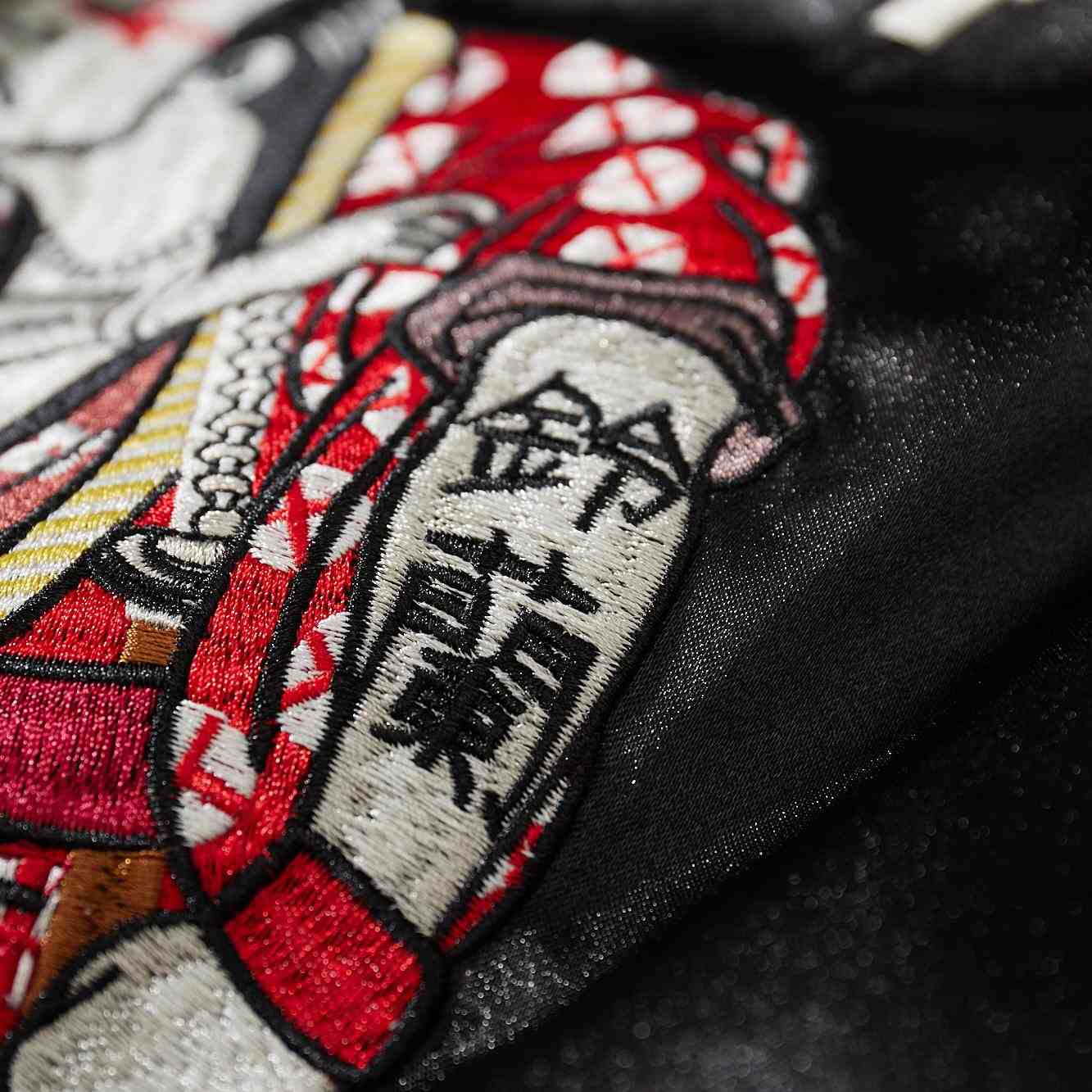 Macro detail of red fighter’s sleeve with kanji Suzuran armband embroidery on Crows Suzuran vs Housen rivalry sukajan.