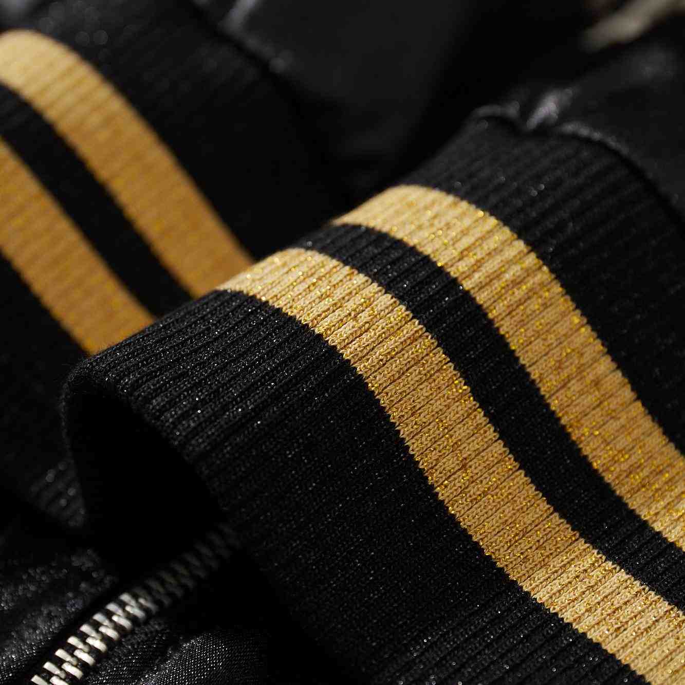 Macro view of glittery black and gold ribbed cuff stripes on Crows Suzuran vs Housen sukajan bomber jacket.