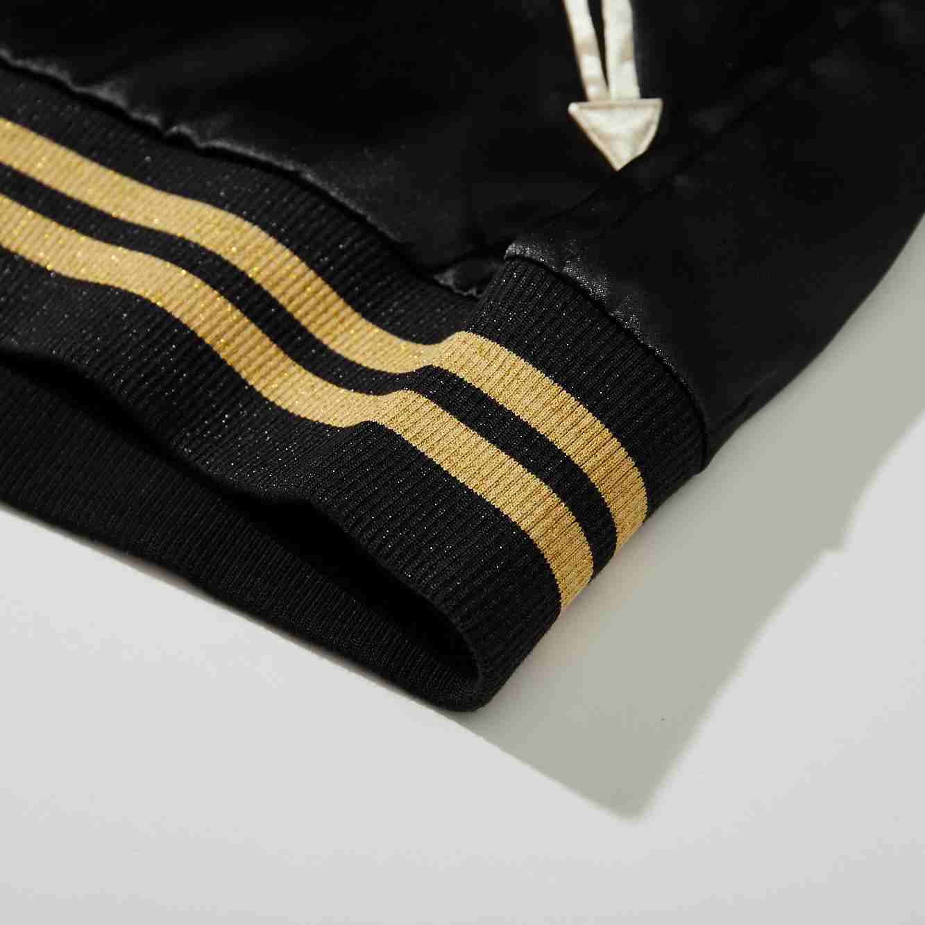 Close-up of striped ribbed hem and lower body of black satin Crows Suzuran vs Housen rivalry sukajan jacket.