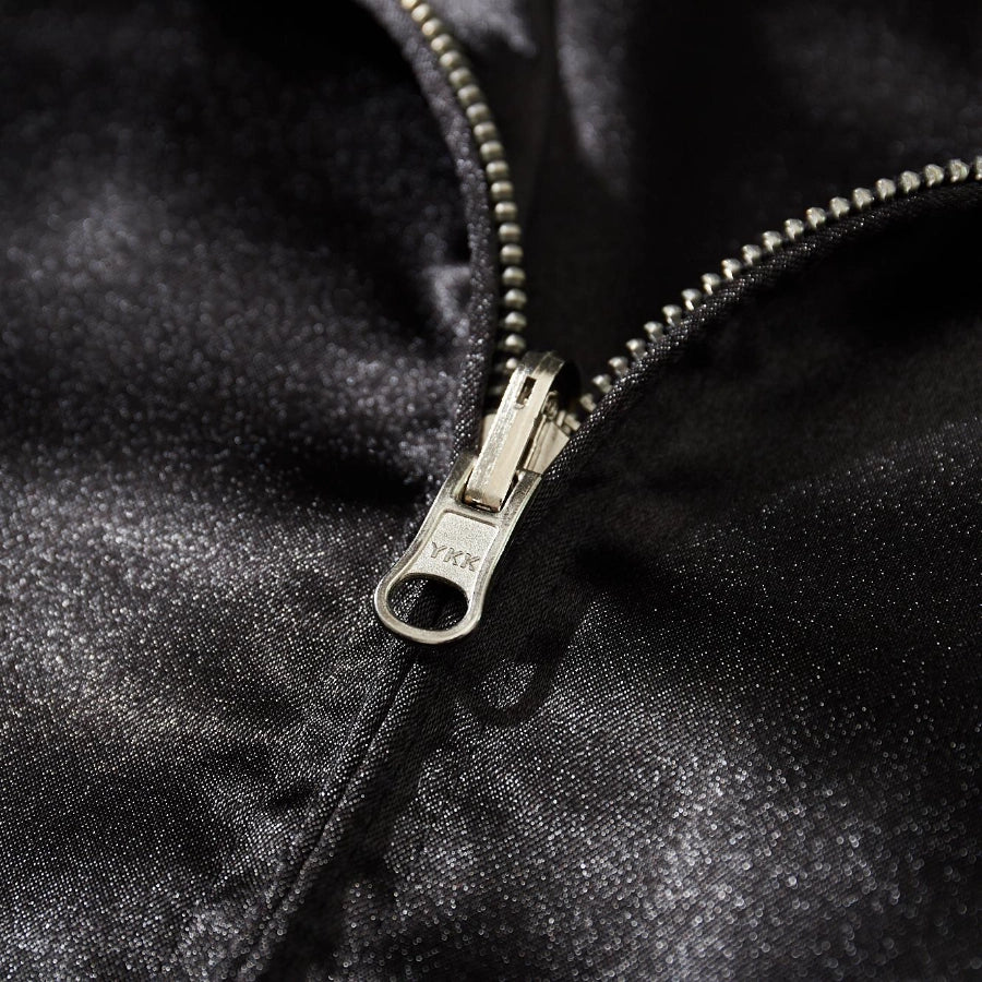 Close-up of durable YKK front zipper on shimmering black satin Dragon Ball Rider sukajan jacket.