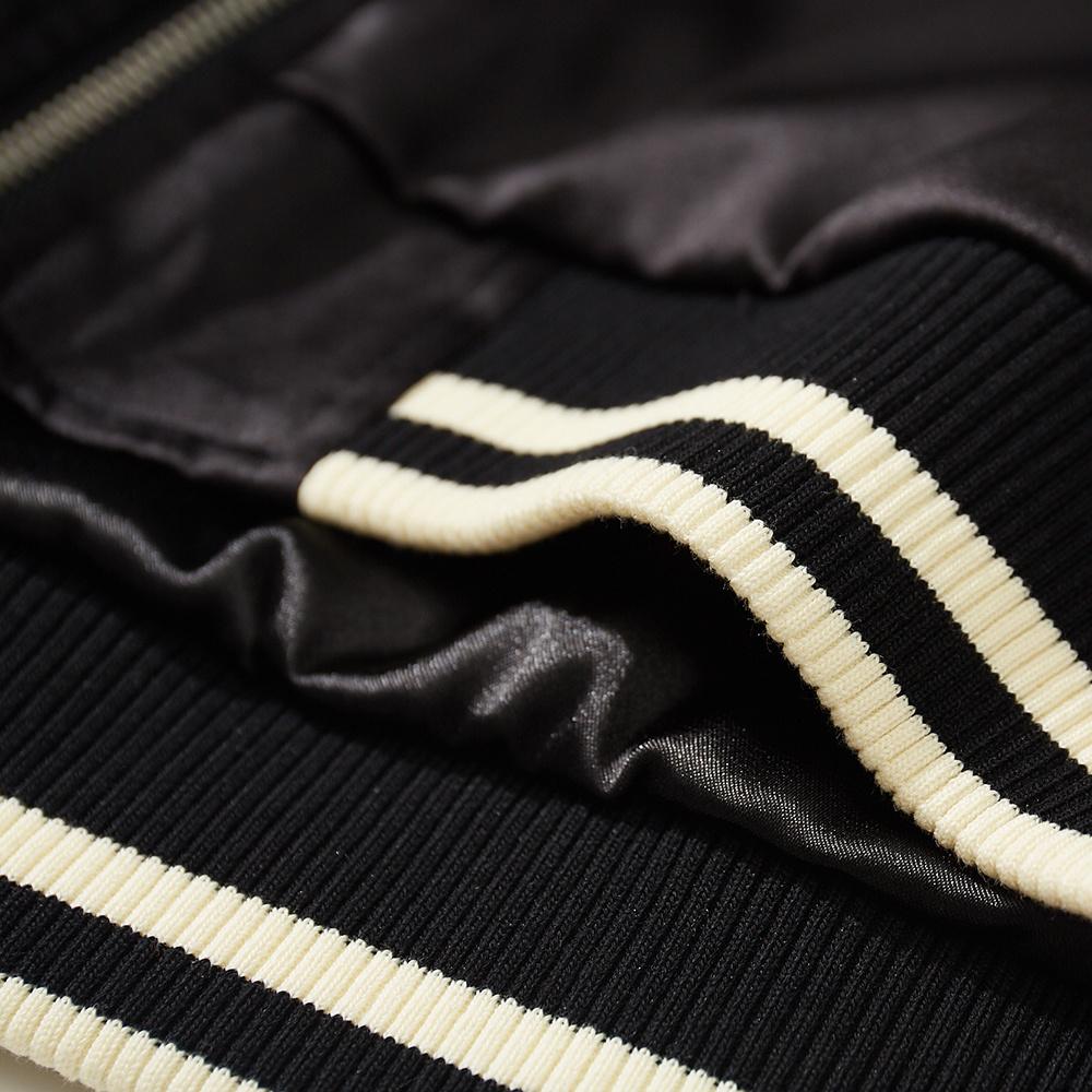 Close-up of ribbed hem with ivory stripes on a black sukajan