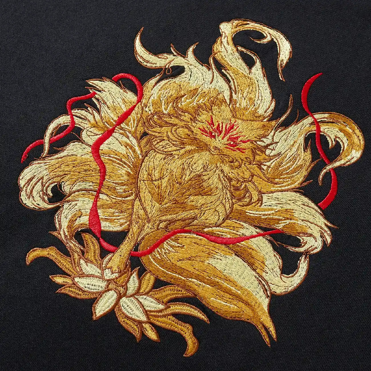 Close up of large golden nine-tailed fox and lotus embroidery on back of black sweatshirt