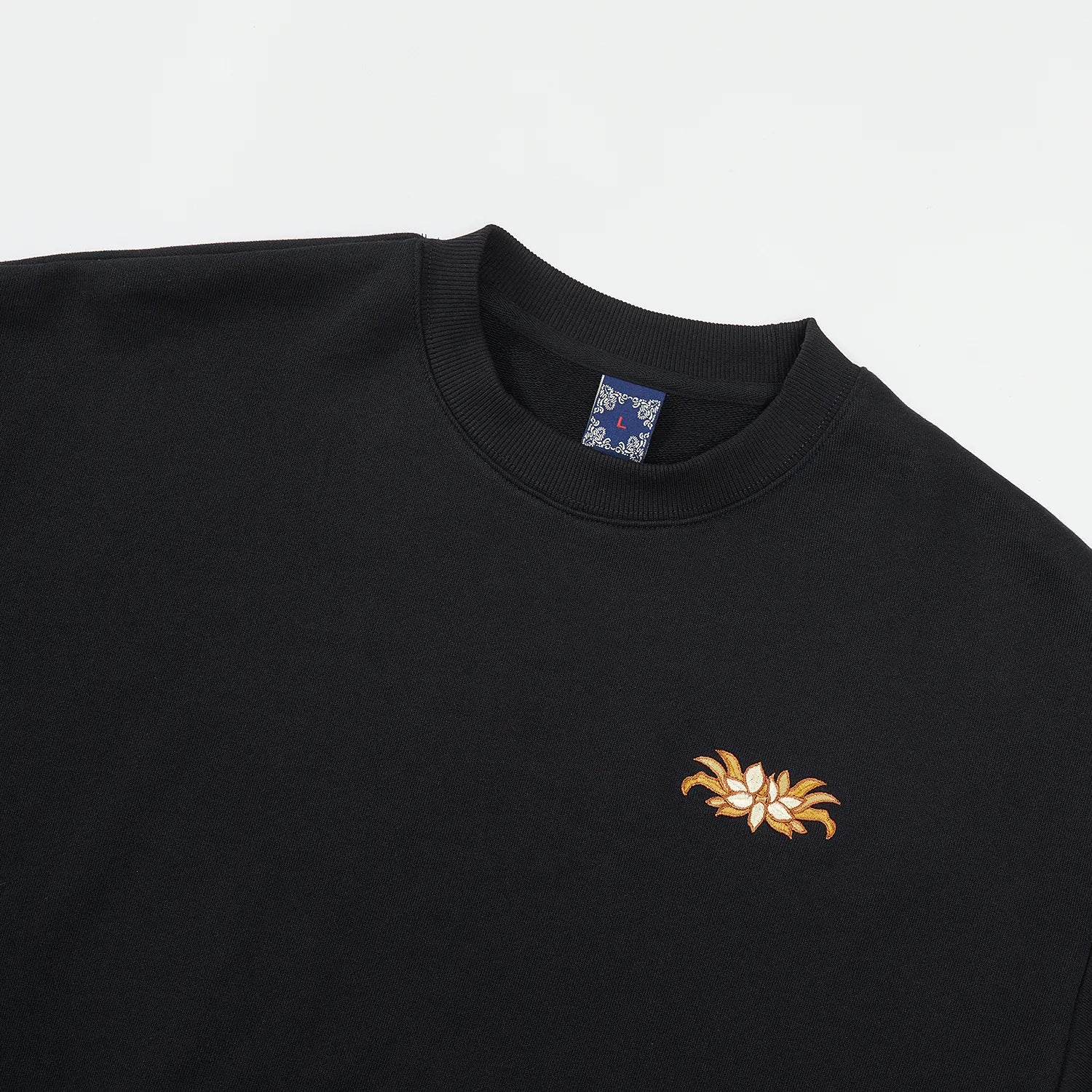 Front upper view of black Nine-Tailed Fox & Lotus sweatshirt with small lotus chest embroidery
