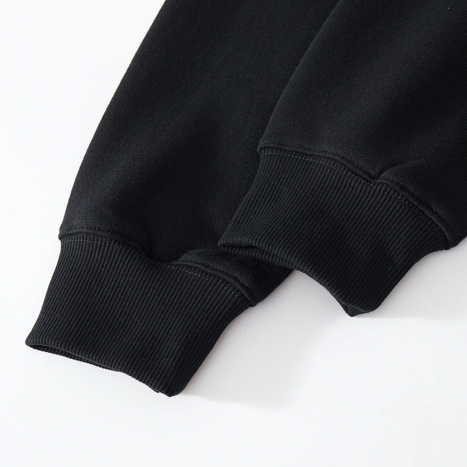 Ribbed cuffs close-up on the black sweatshirt showing stretch and dense knitting