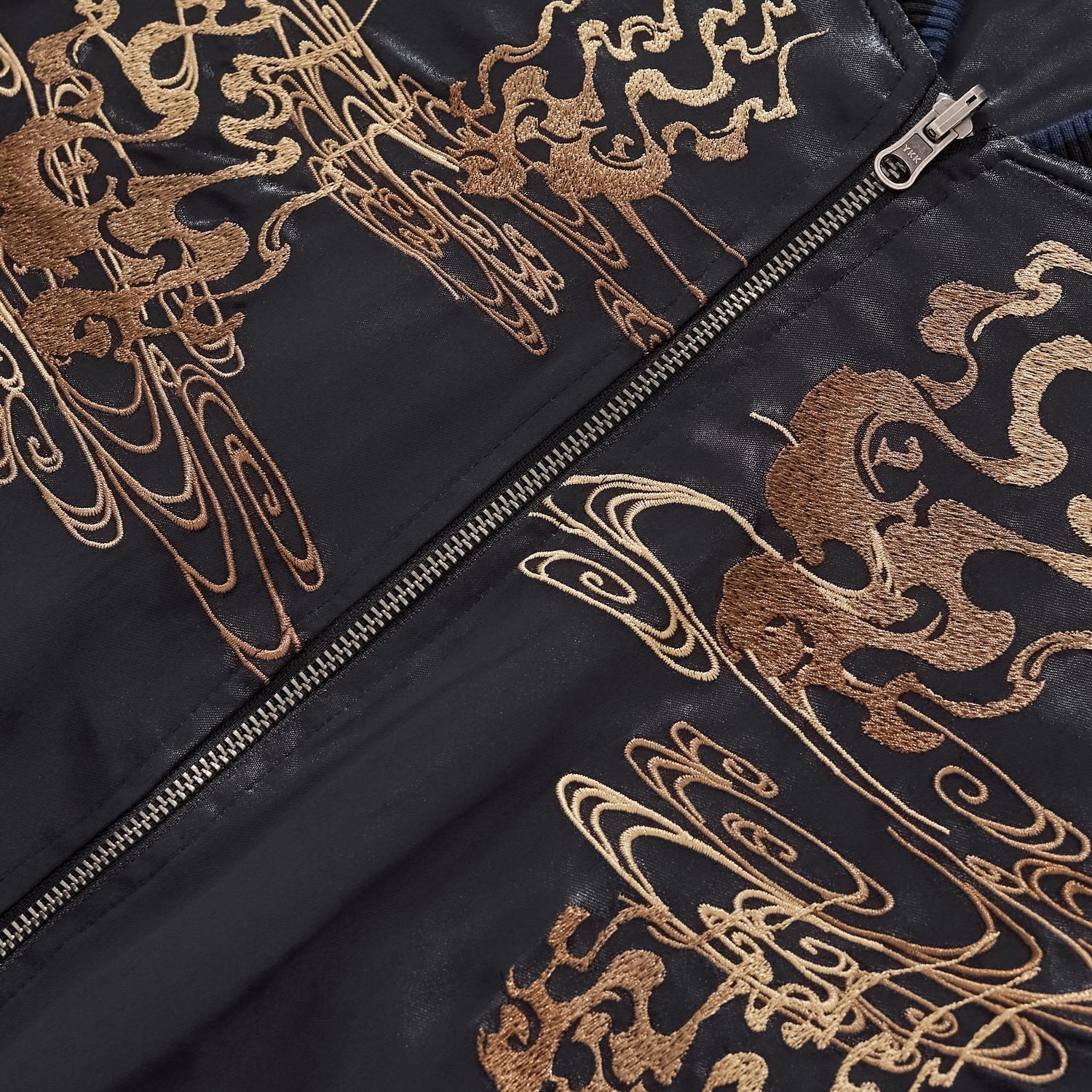 Detail of the durable metal zipper and intricate chest embroidery on black satin.
