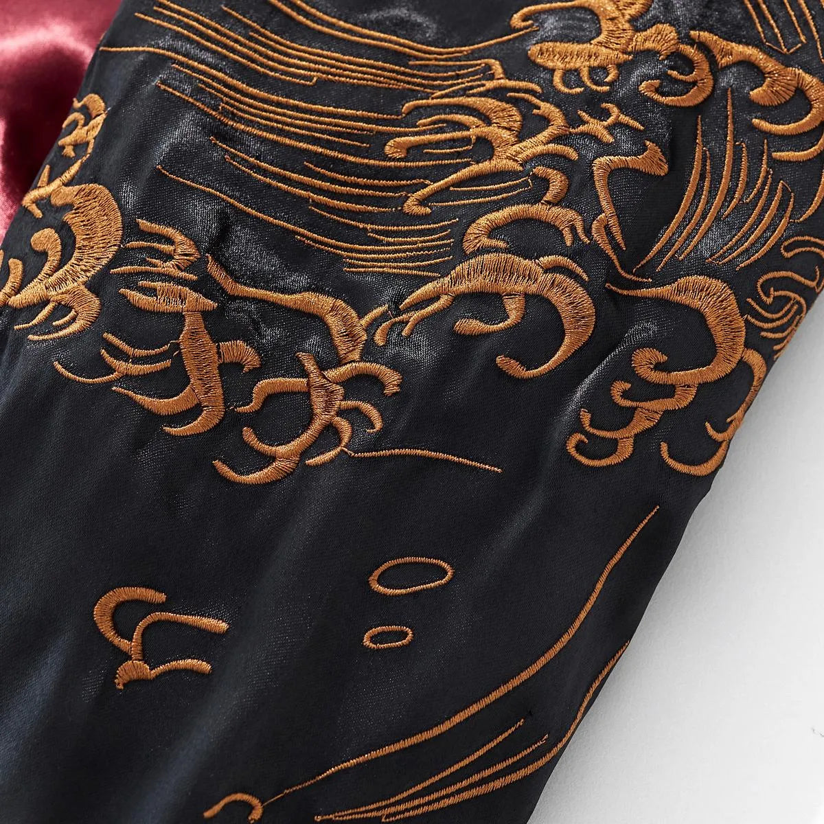 Close-up of intricate golden wave embroidery on the satin sleeve.