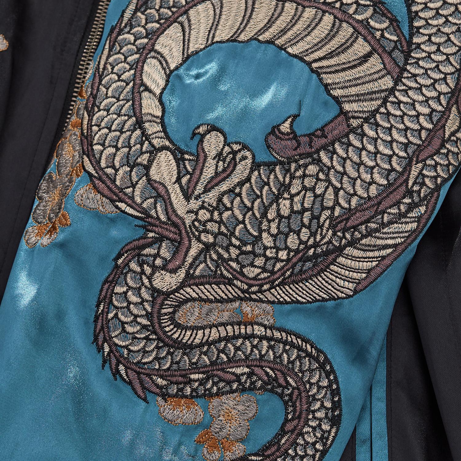 Intricate embroidery detail of the silver dragon body coiling down the blue satin sleeve.