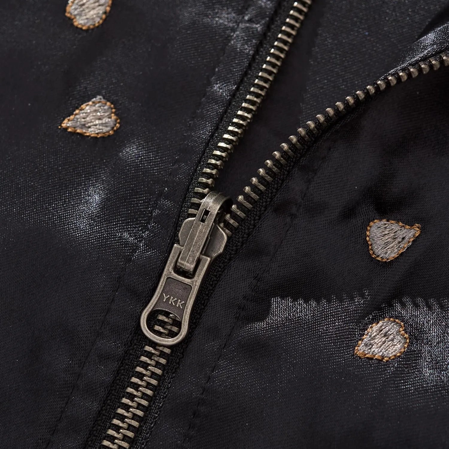Macro shot of the antique silver YKK zipper pull surrounded by embroidered sakura petals.