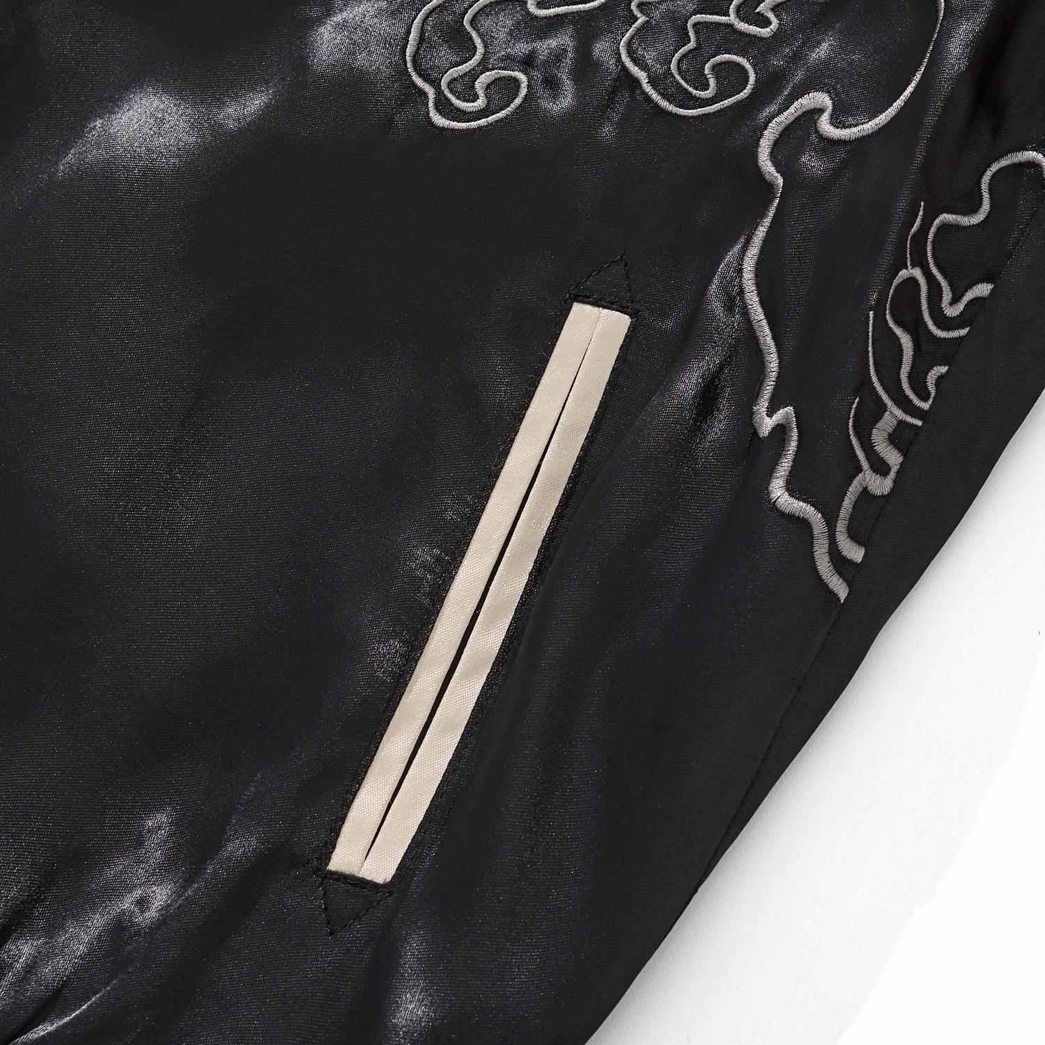 Front pocket welt detail on black body with cloud embroidery lines.