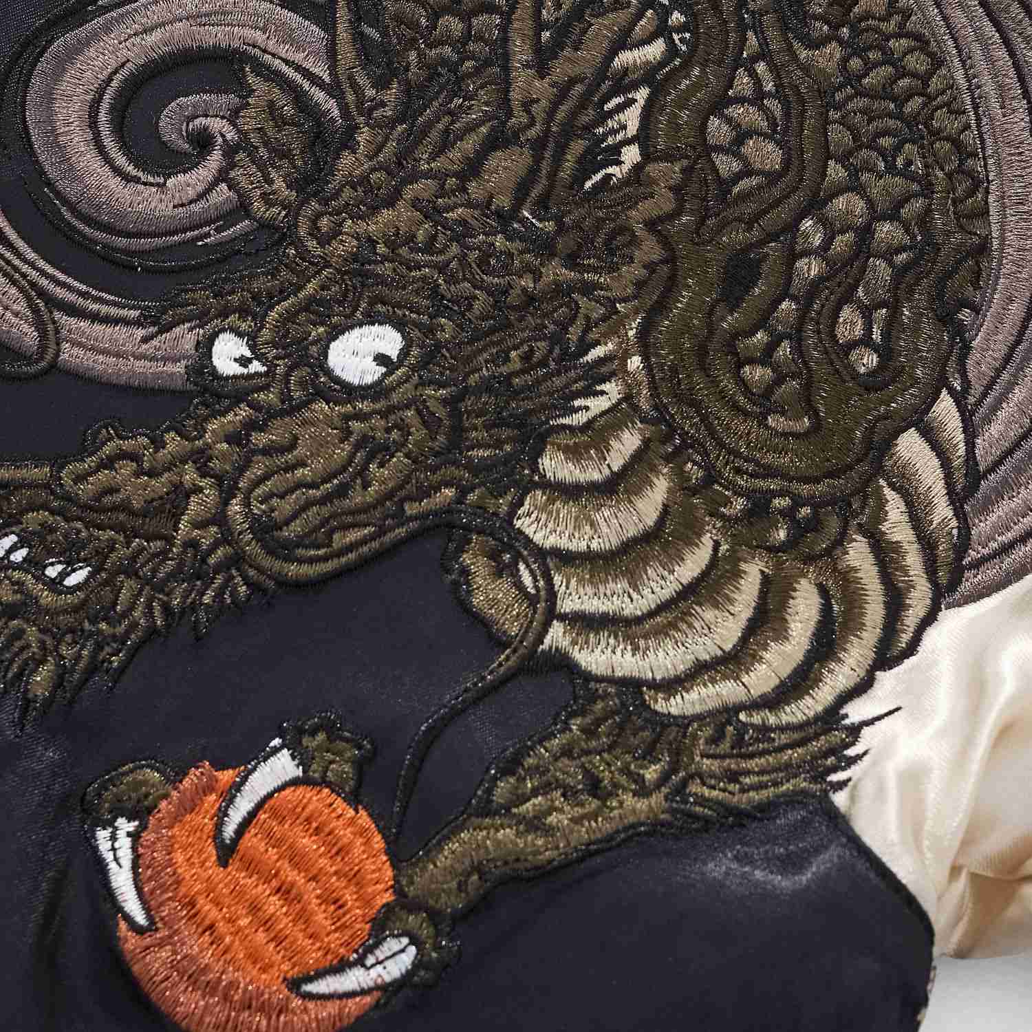 Macro detail of upper dragon clutching flaming pearl embroidery on Twin Dragons & Sakura embroidered sukajan jacket.