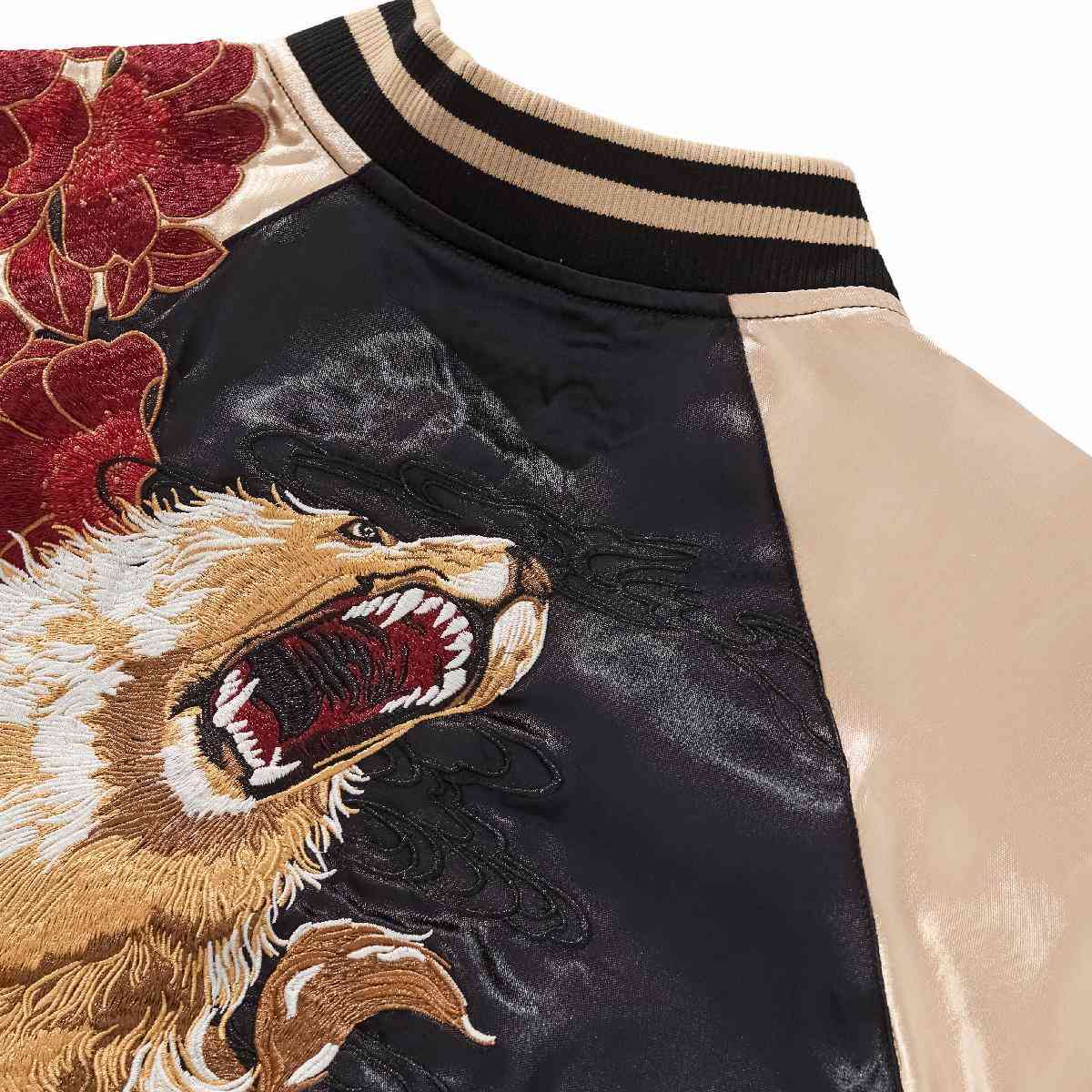 Collar detail — Beige sleeve joins black body; roaring lion embroidery with striped rib.