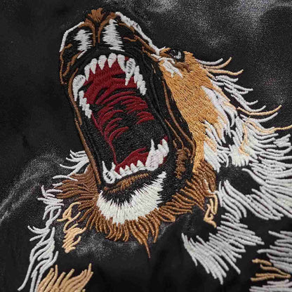 Embroidery close-up — open-mouth lion with dense stitches and shading.
