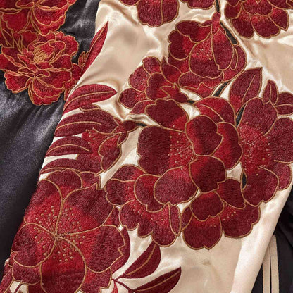Close-up — white sleeve with layered red peony embroidery and gold outlines