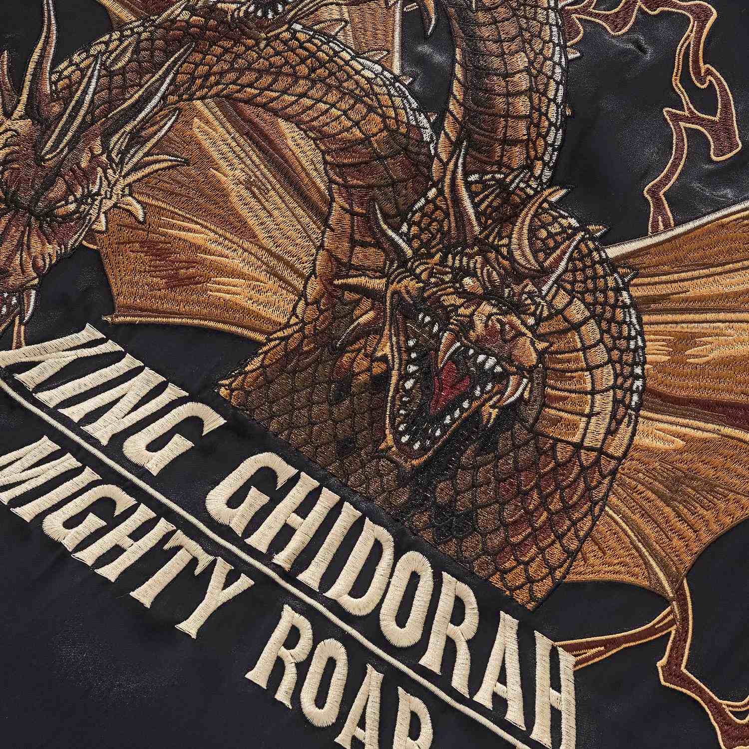 King Ghidorah head embroidery close-up over Mighty Roar text.