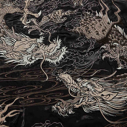 Embroidery close-up — intertwined dragons rendered with layered metallic threads.