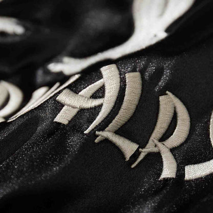 Macro detail of curved “Rivalry” embroidery letters on black satin Crows Suzuran vs Housen sukajan jacket.