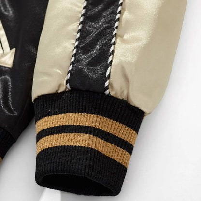 Close-up of beige sleeve panel and black-gold striped ribbed cuff on Dragon Ball sukajan jacket.