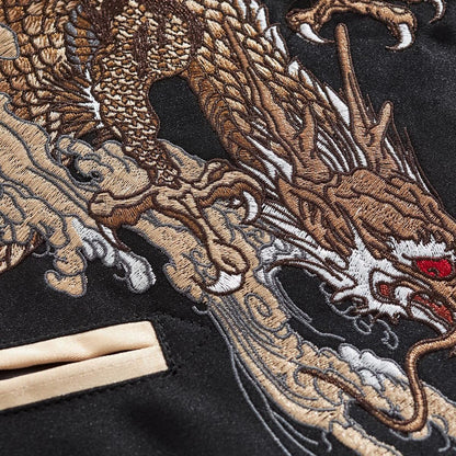 Macro of dragon embroidery — scales, clouds, and whiskers in dense, high-relief threadwork.
