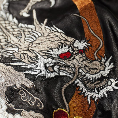 Dragon head embroidery detail with arcing crescent and fine whiskers.