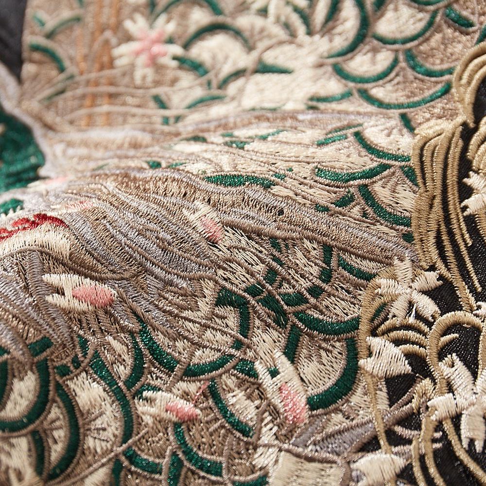 Close-up of layered dragon scales embroidery with sakura petals on a black sukajan