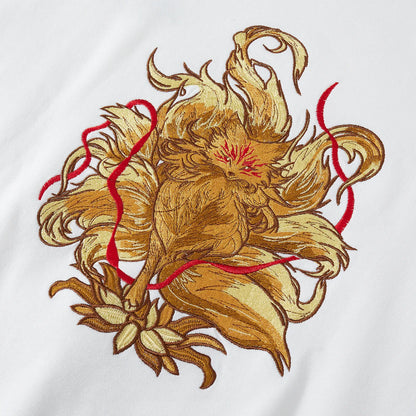 Close up of large nine-tailed fox and lotus embroidery with red ribbons on back of white sweatshirt.