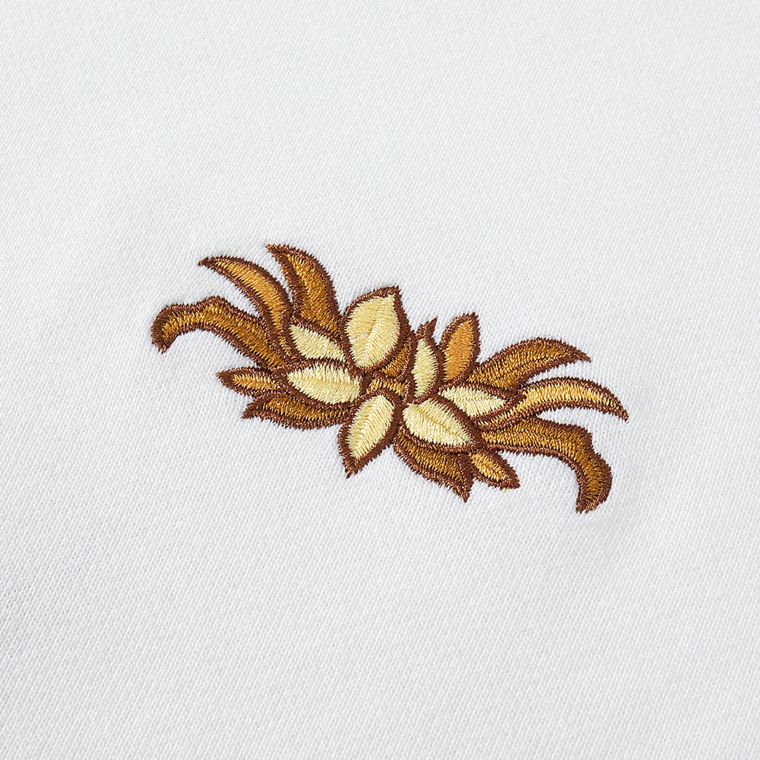 Detail of small gold lotus emblem embroidery on front of Nine-Tailed Fox & Lotus sweatshirt.