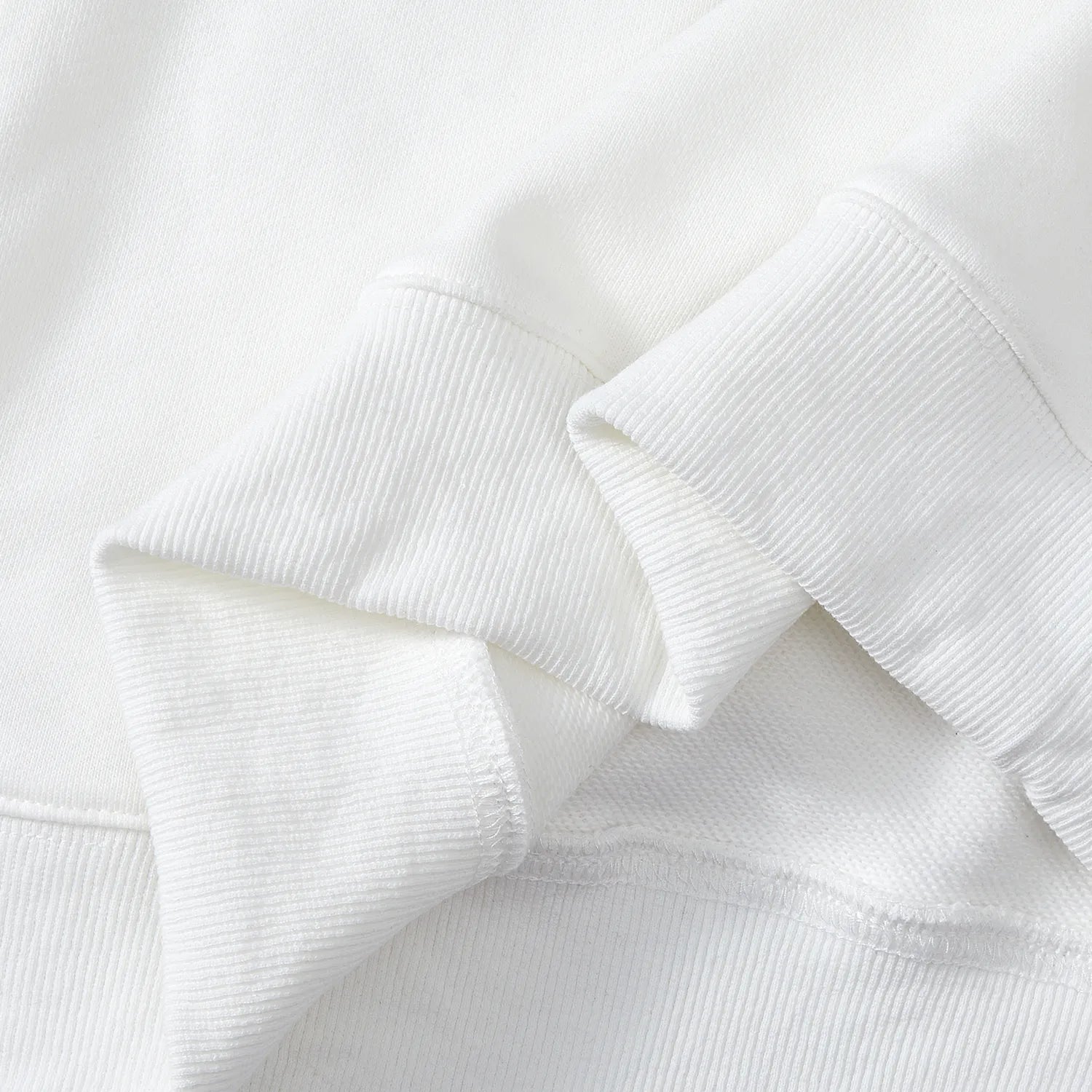 Detail of ribbed cuffs and hem on white Nine-Tailed Fox & Lotus sweatshirt.