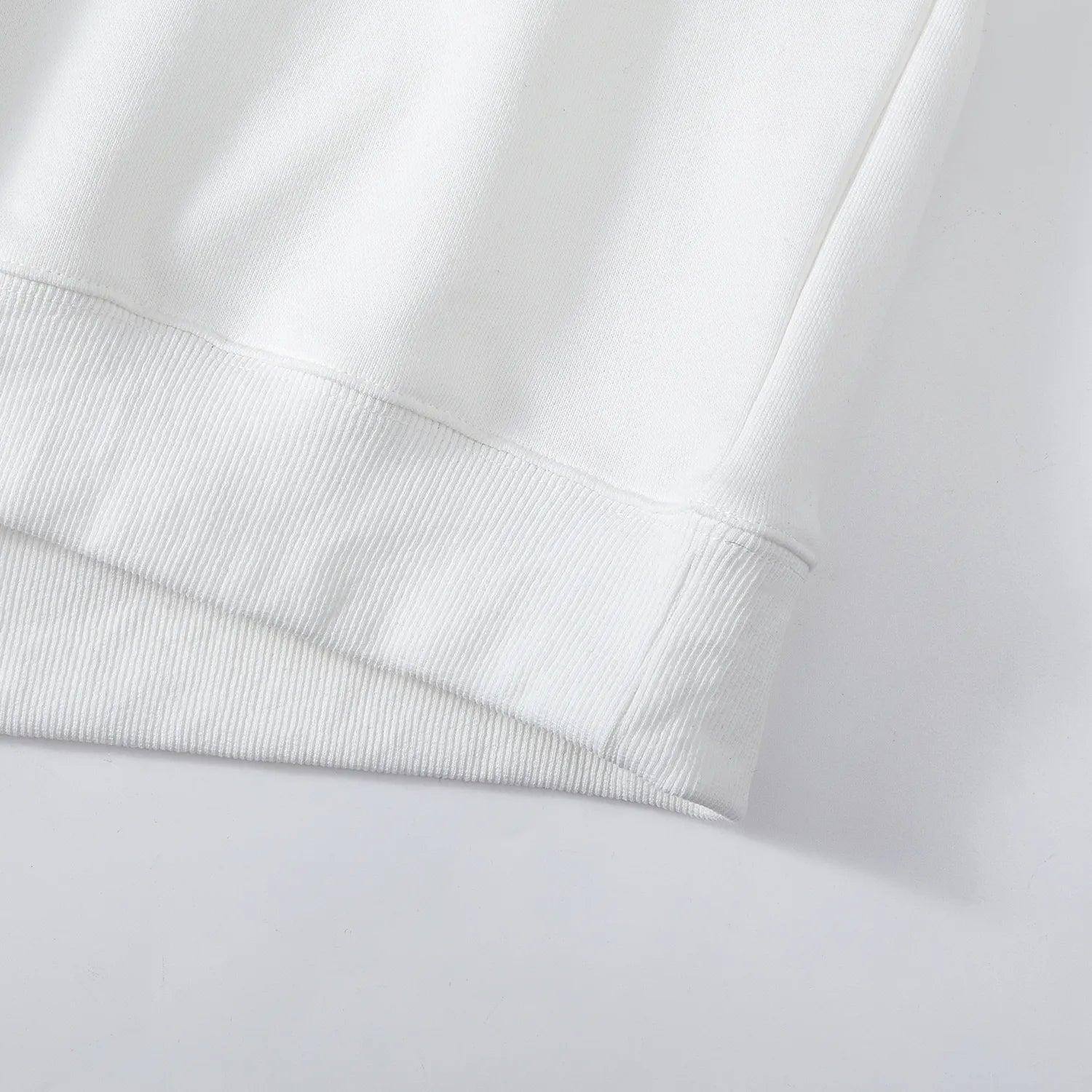 Detail of ribbed bottom hem on white Nine-Tailed Fox & Lotus sweatshirt.