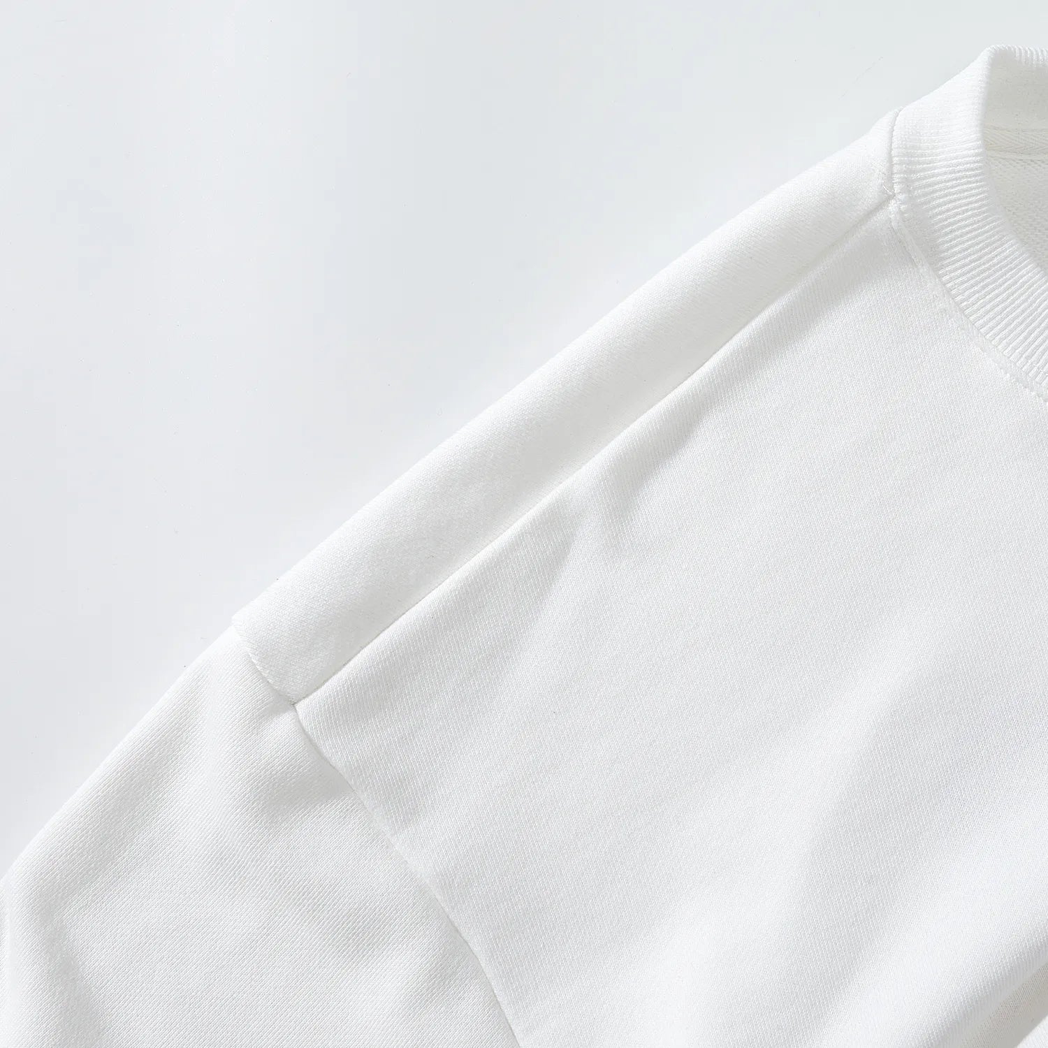 Close up of smooth shoulder construction and white fabric on Nine-Tailed Fox & Lotus sweatshirt.