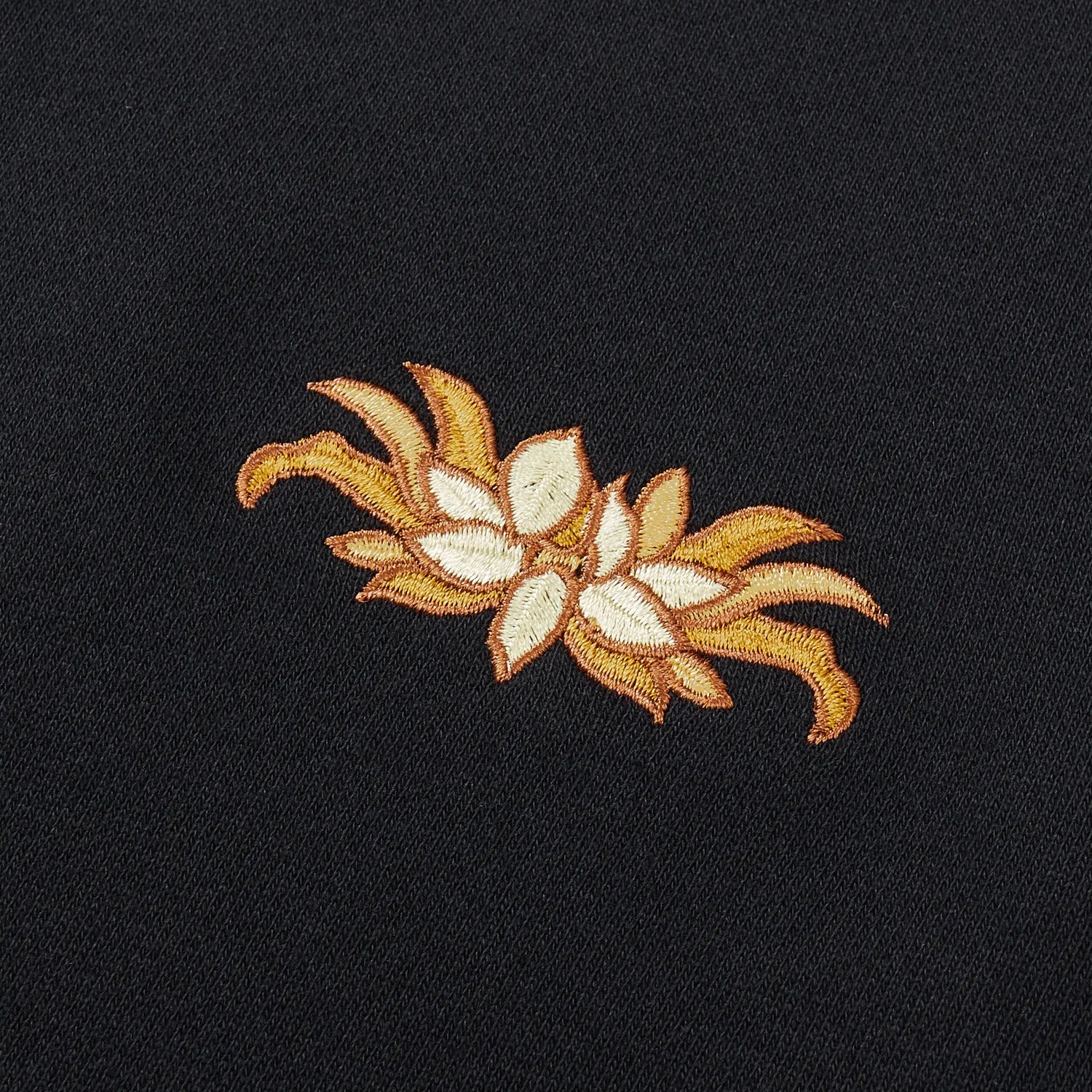 Detail of golden lotus flower embroidery on chest of black Nine-Tailed Fox & Lotus sweatshirt