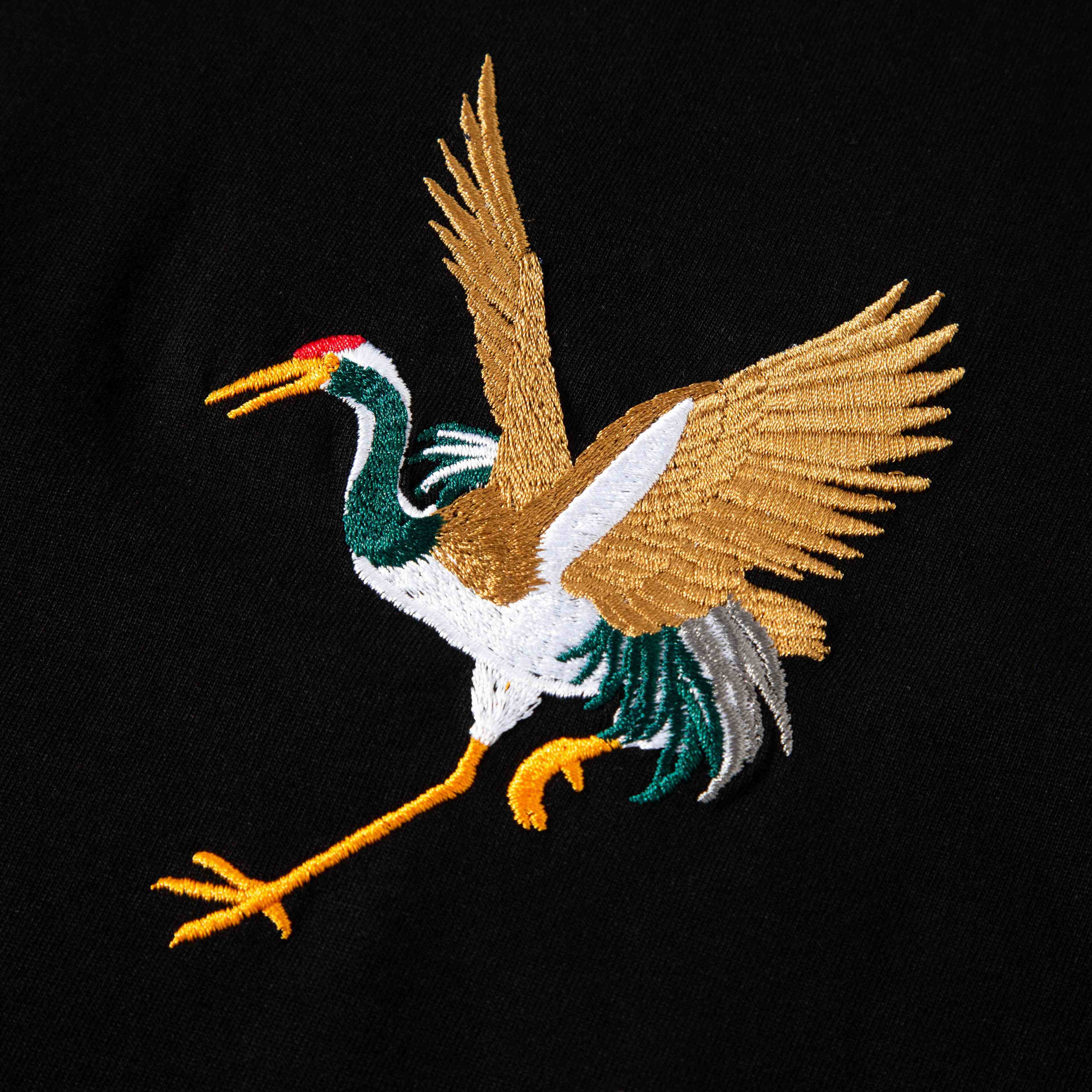 Close-up of chest crane embroidery—dense stitching and layered wings