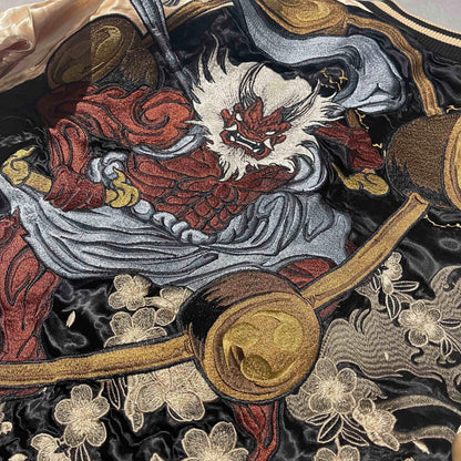 Close-up of Raijin embroidery with thunder drums and sakura on a reversible sukajan jacket.