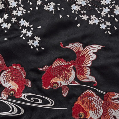 Back embroidery close-up of the koi trio beneath falling blossoms