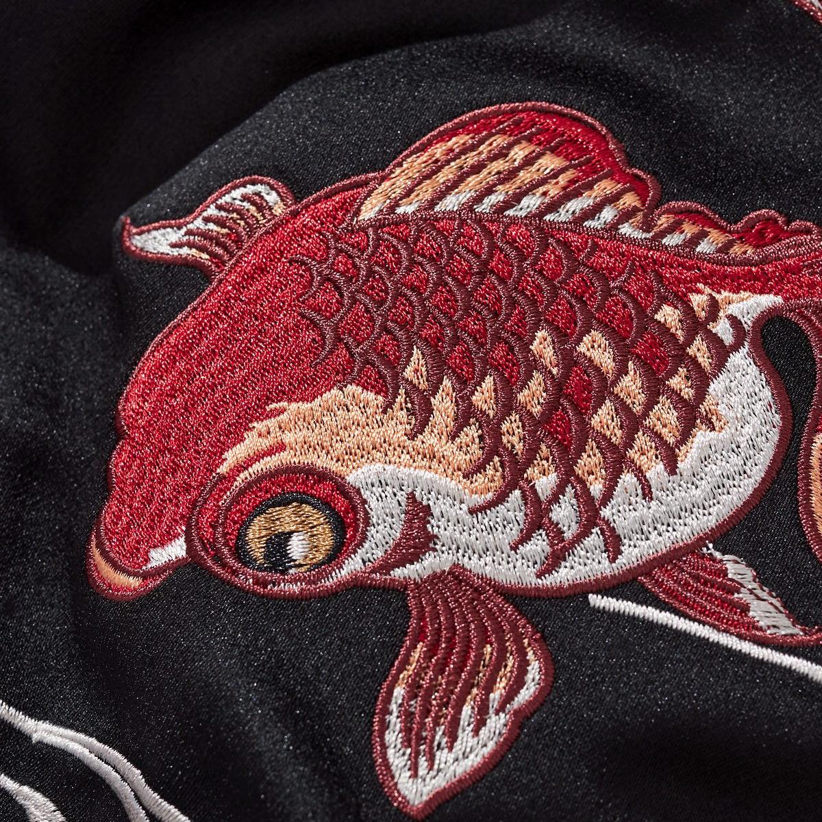 Macro embroidery of a goldfish showing layered scales and crisp stitching