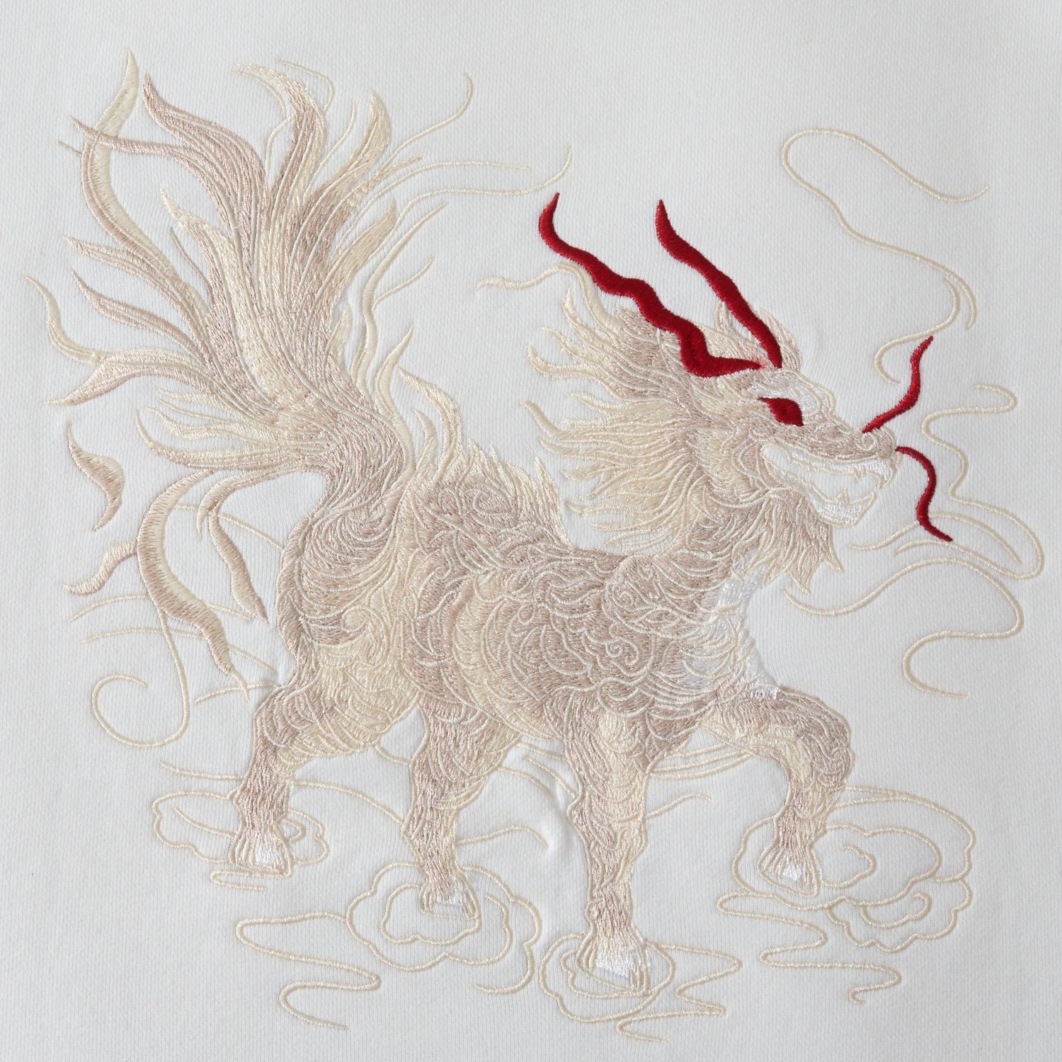 Close-up of Kirin embroidery on the white sweatshirt with layered, textured threadwork