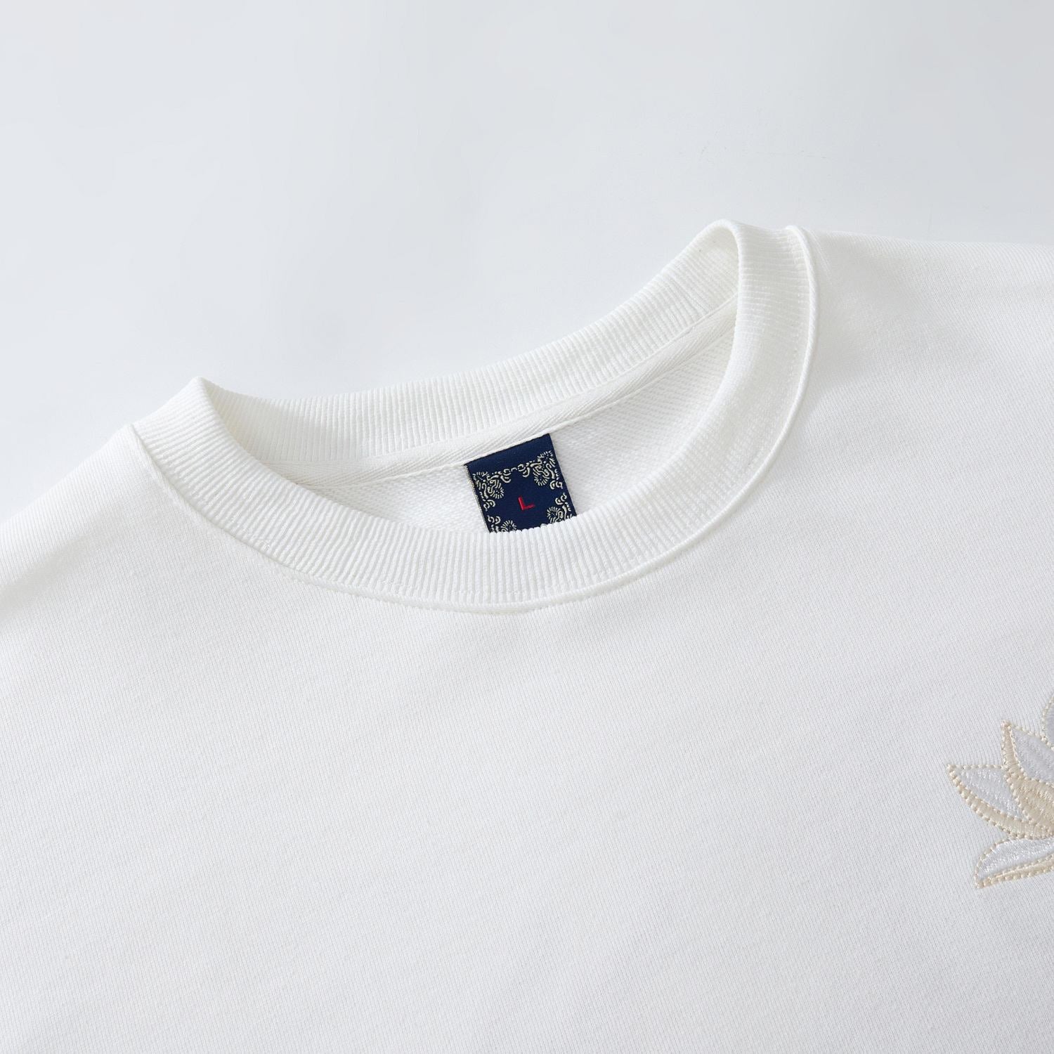 Ribbed crewneck detail of the white sweatshirt showing clean construction