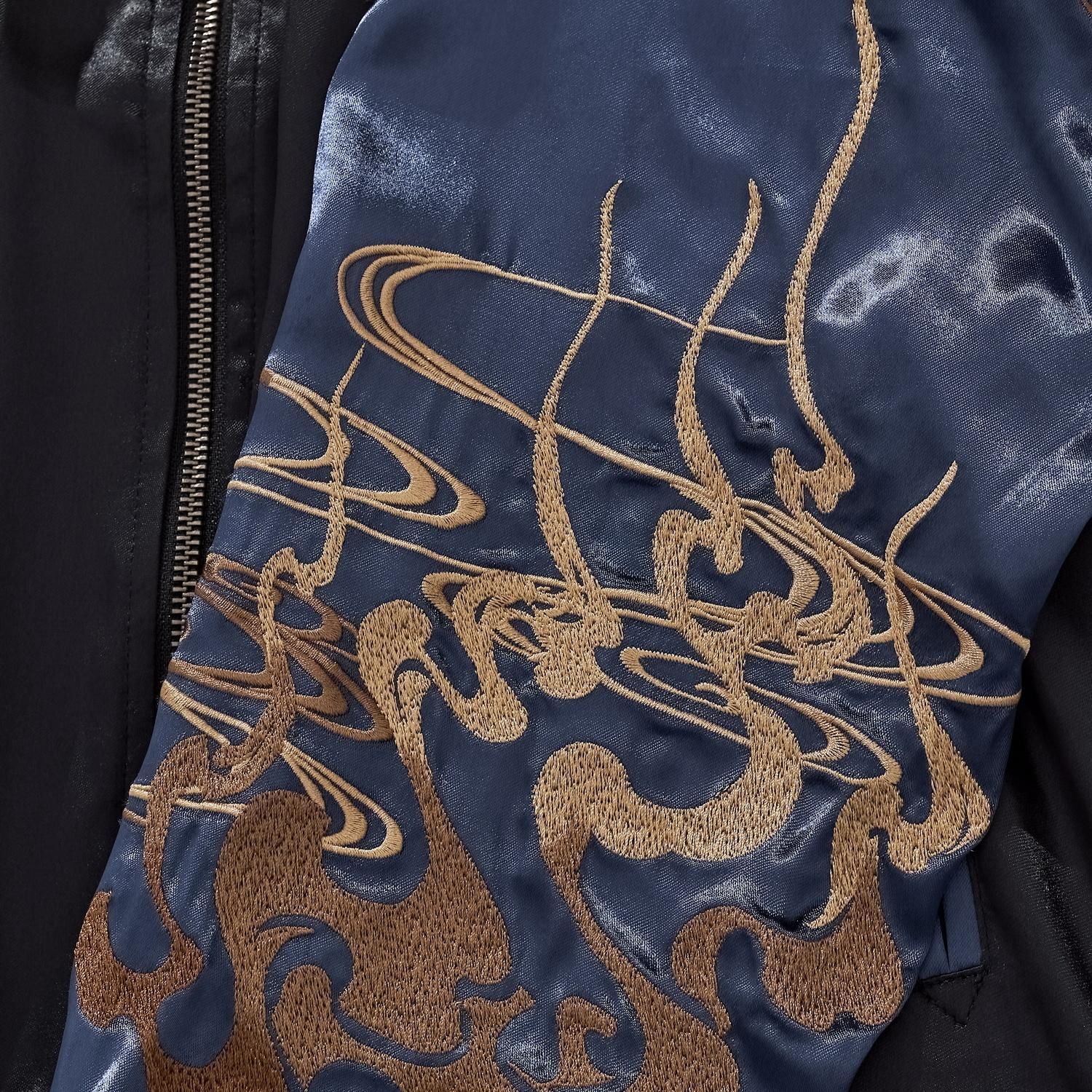 Detail of the golden cloud and smoke embroidery on the midnight blue satin sleeve.