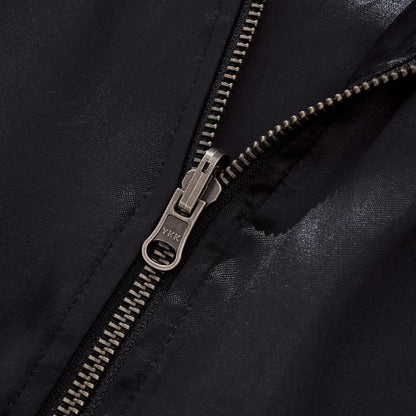Macro photography of the durable YKK metal zipper pull on black satin fabric.