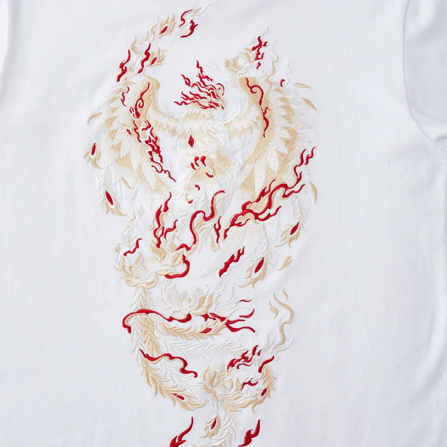 Detailed shot of the red and gold Phoenix embroidery contrasting against the pure white tee.