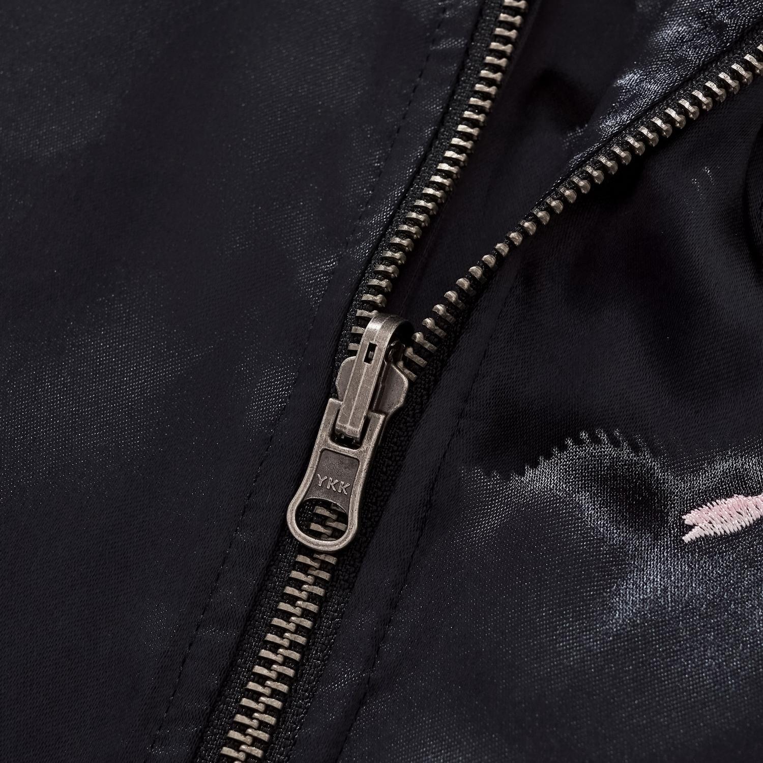 Macro photography of the antique silver YKK zipper pull on black rayon fabric.