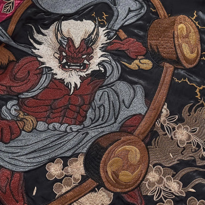 Extreme close-up of the Red Thunder God (Raijin) face embroidery on the burgundy jacket.