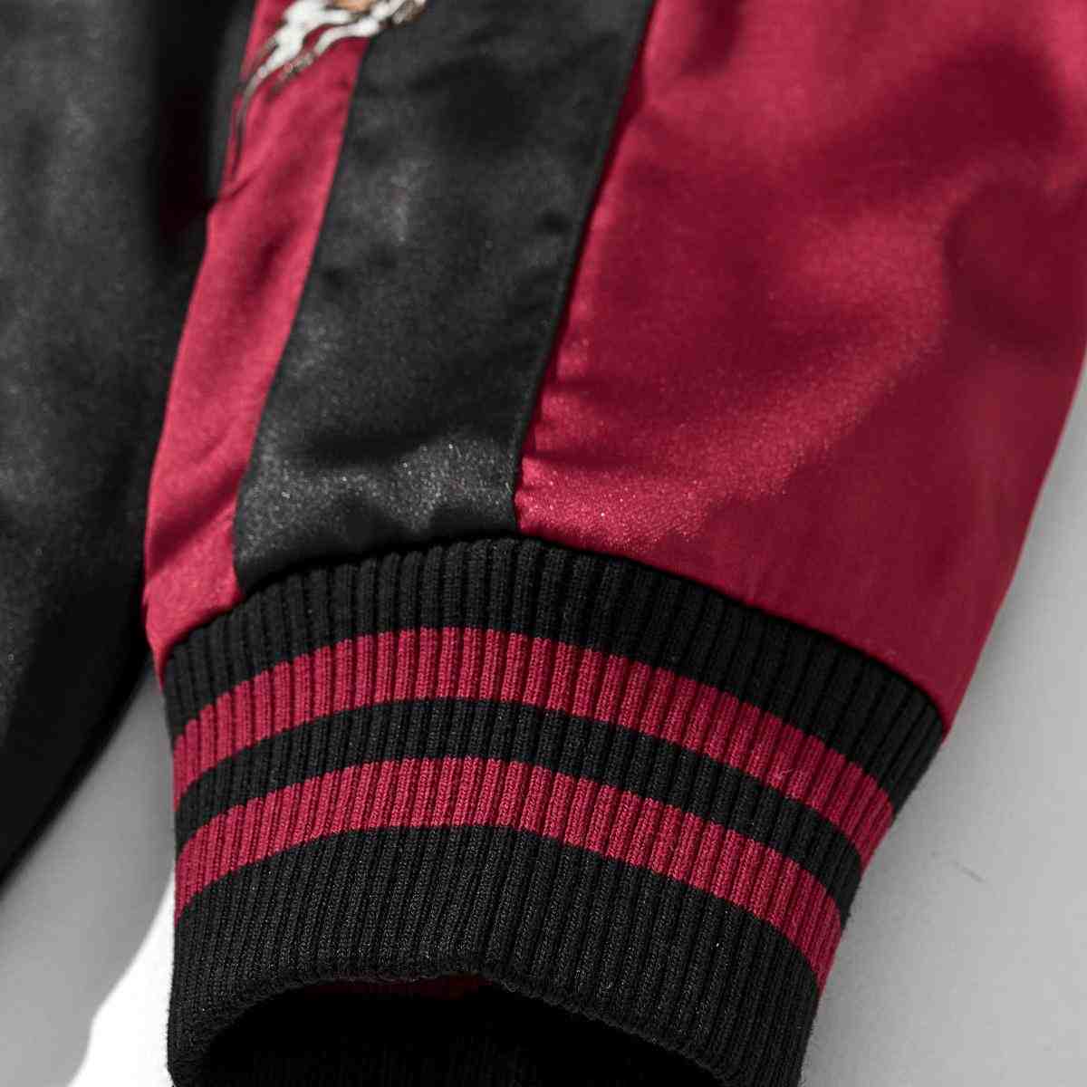 Close-up of ribbed cuff on burgundy color reversible dragon & peony sukajan jacket; black and burgundy striped knit.