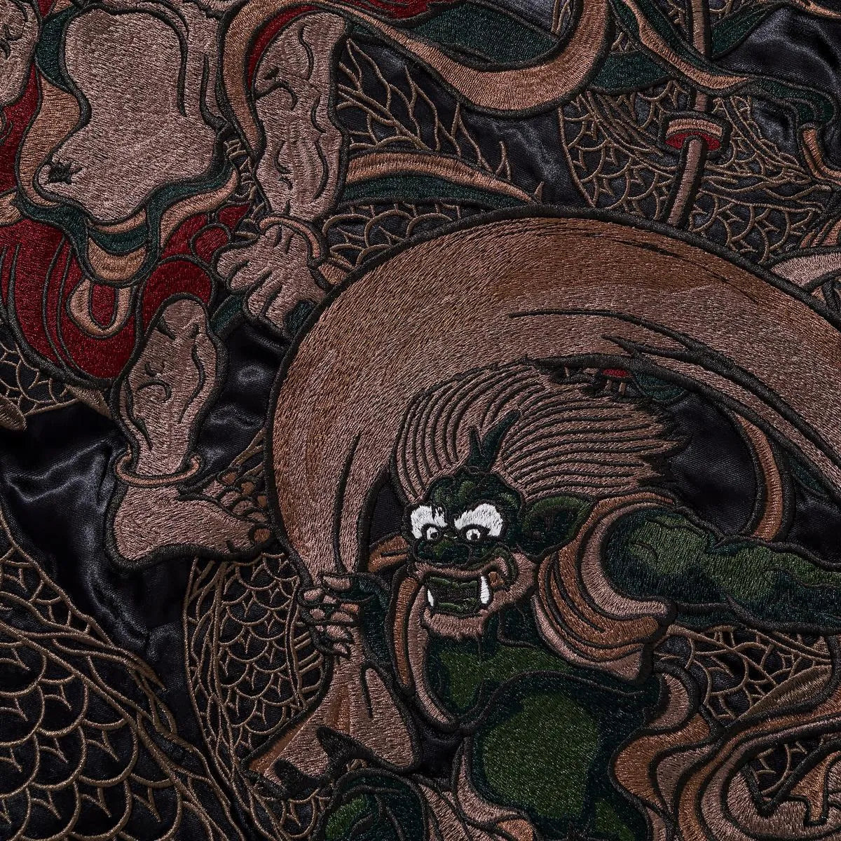 Extreme close-up of the Thunder God (Raijin) embroidery showing facial expression and craftsmanship.