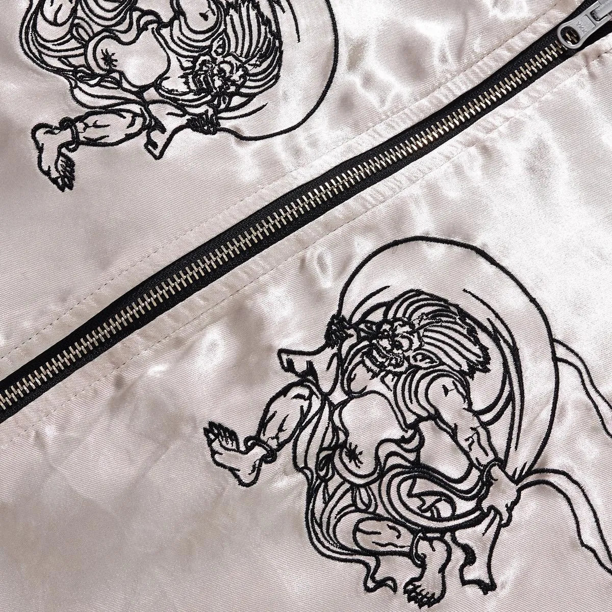 Detail of the minimalist line-art embroidery on the reverse satin side with zipper hardware.