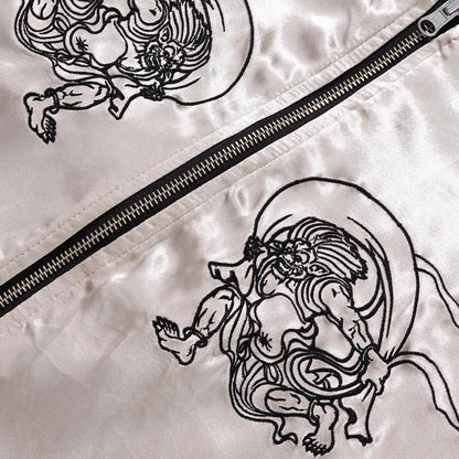 Detail of the minimalist line-art embroidery on the reverse satin side with zipper hardware.