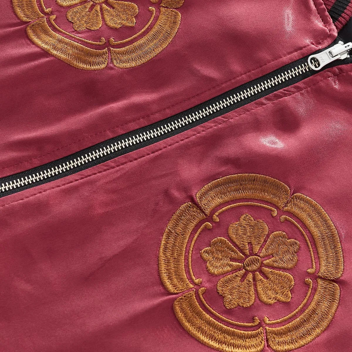 Detail of the dual floral crests embroidered on the chest with zipper hardware.